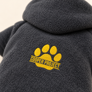 Close-up of the embroidered Cooper Project paw on charcoal fleece
