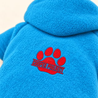 Close-up of the embroidered Cooper Project paw on sky fleece