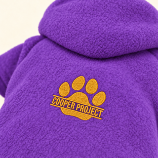 Close-up of the embroidered Cooper Project paw on violet fleece